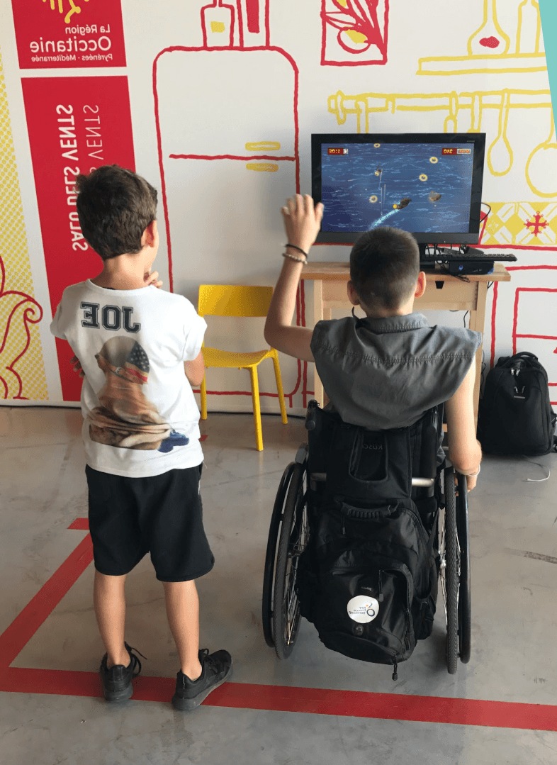 Un enfant et un enfant en fauteuil roulant jouent à un jeu piloté par caméra